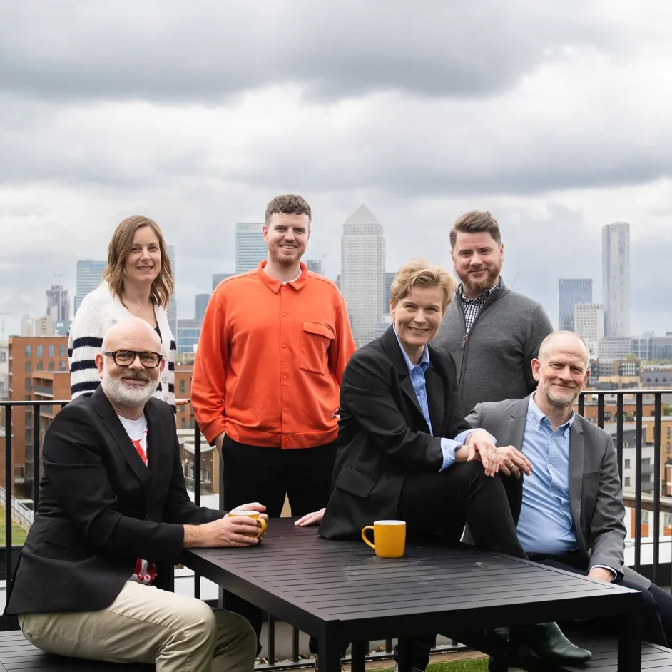 The Simple Revolutions team sat at a table on a balcony with a city in the background