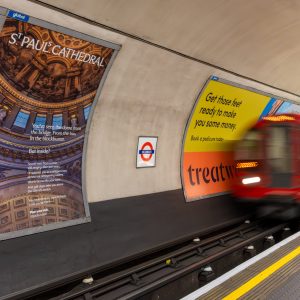 Tube pulling into a station with a large St Paul's ad on the wall. 