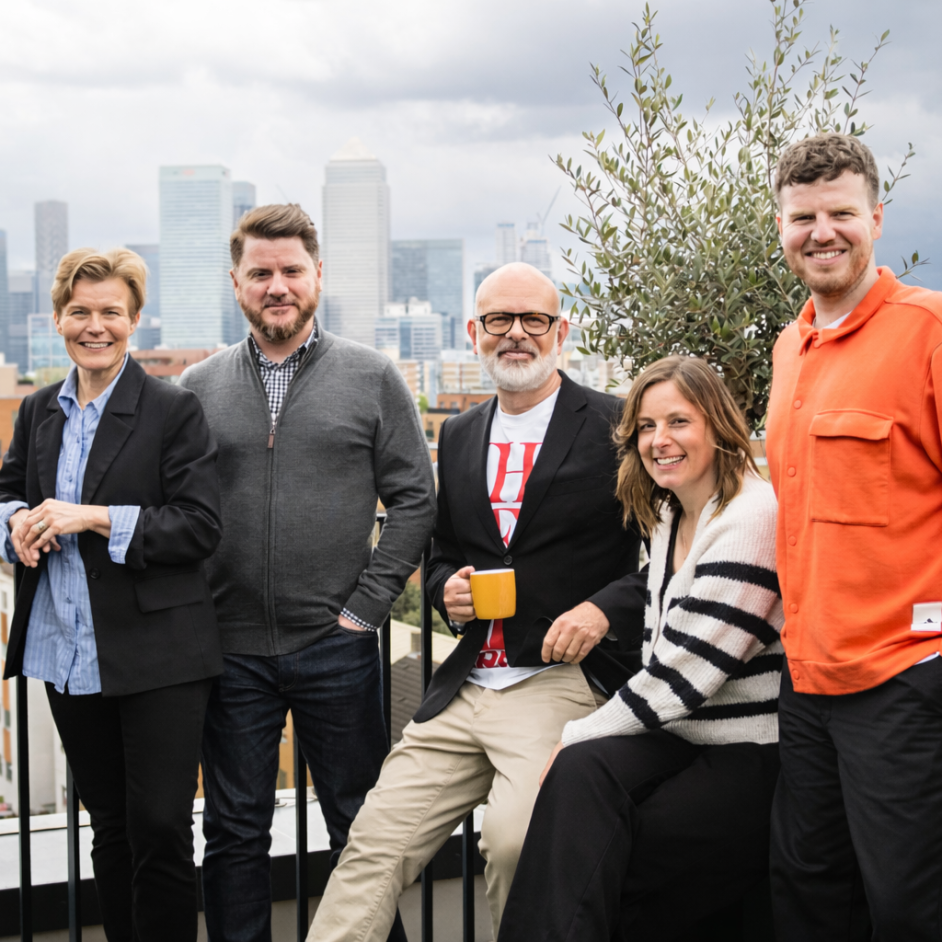 Simple Revolution team of five sat at a table with the London skyline in the background