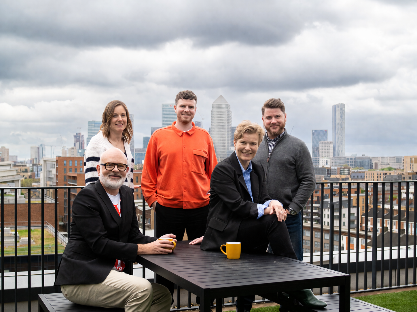 Simple Revolution team of five sat around a table outside with the london skyline in the background