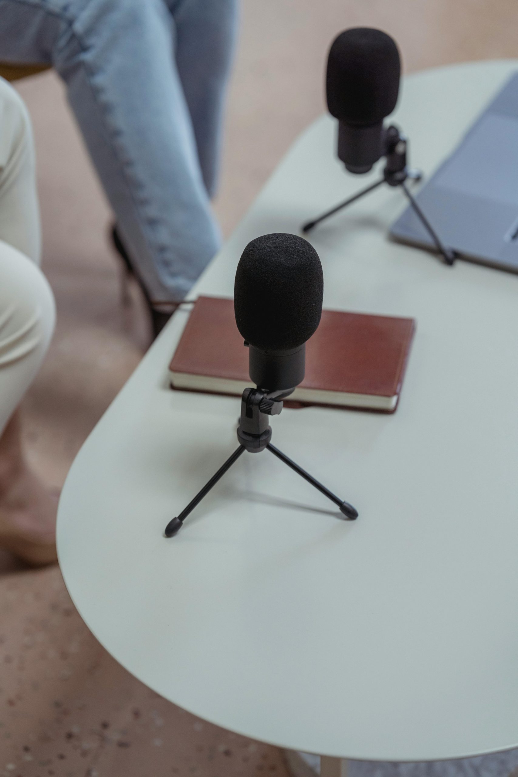 Two microphones on a white table with a notebook